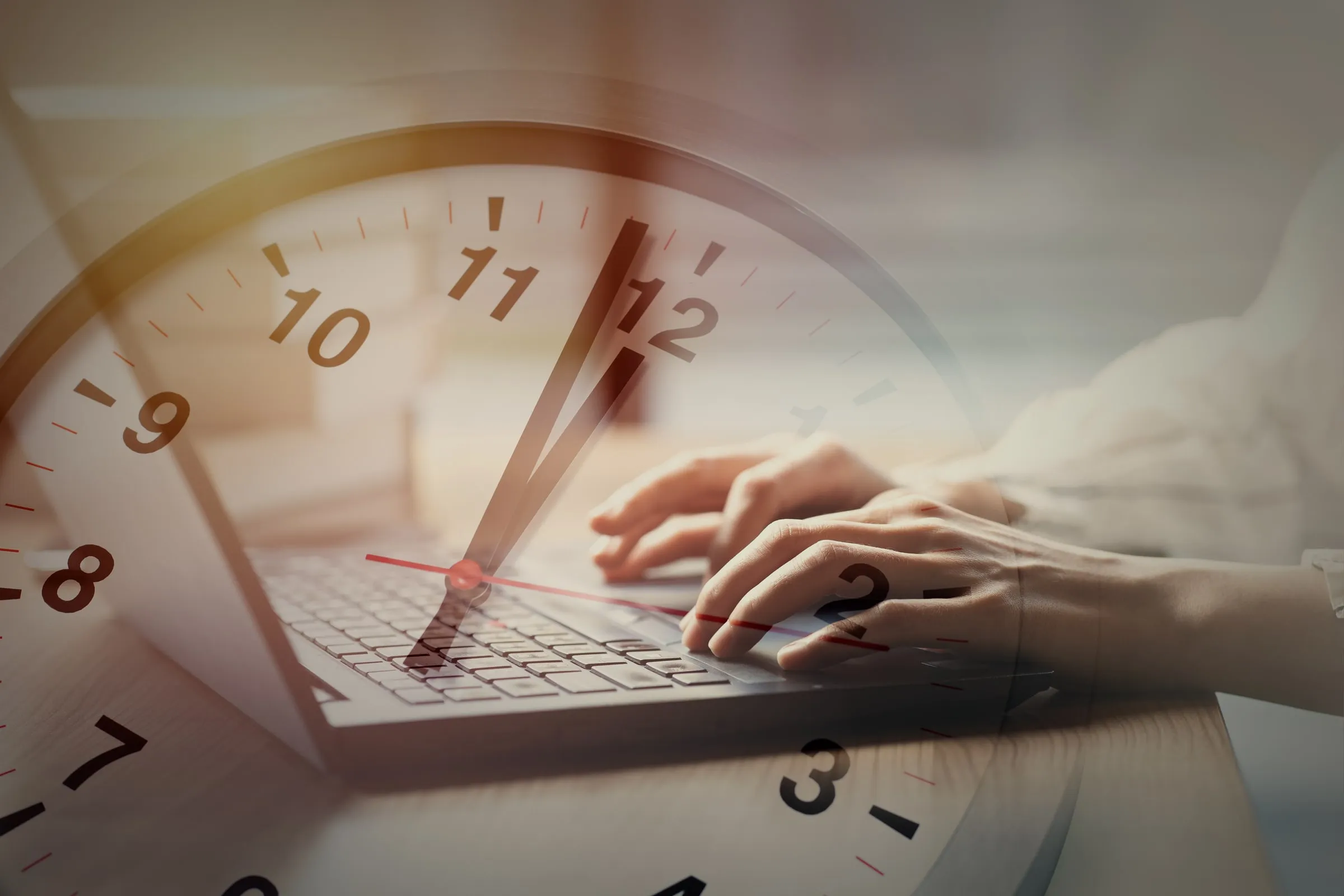 Hände auf dem Notebook, darüber eine Uhr als Sinnbild für eine ablaufende Frist.